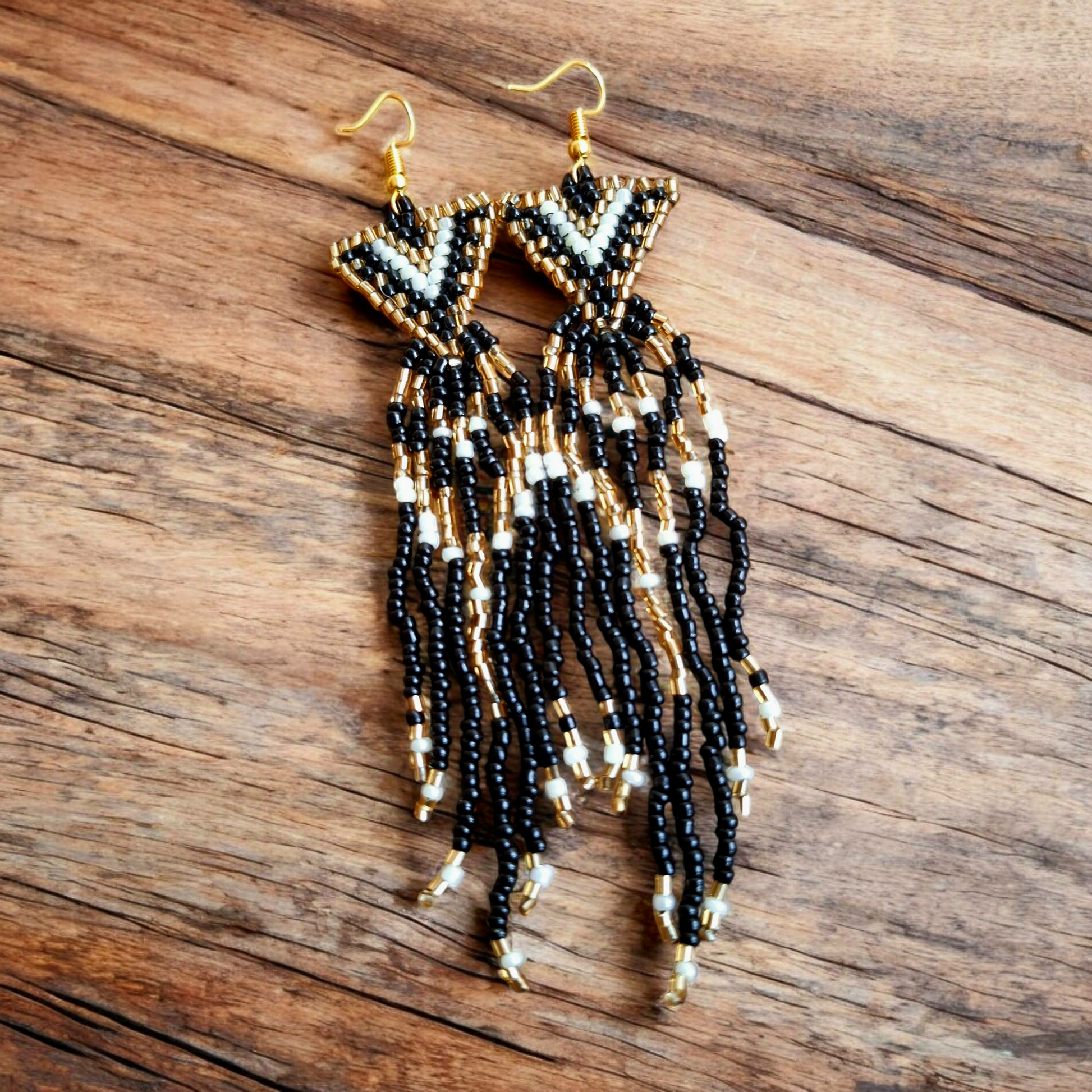 Handmade cascade earrings in an elegant black, white, and gold with a waterfall-inspired design on a wooden plate.