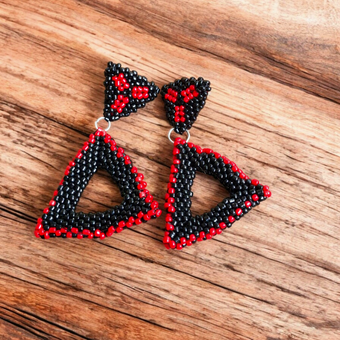 Handmade Paired Peaks earring featuring two stacked triangles in midnight black with hints of red on a wooden background.