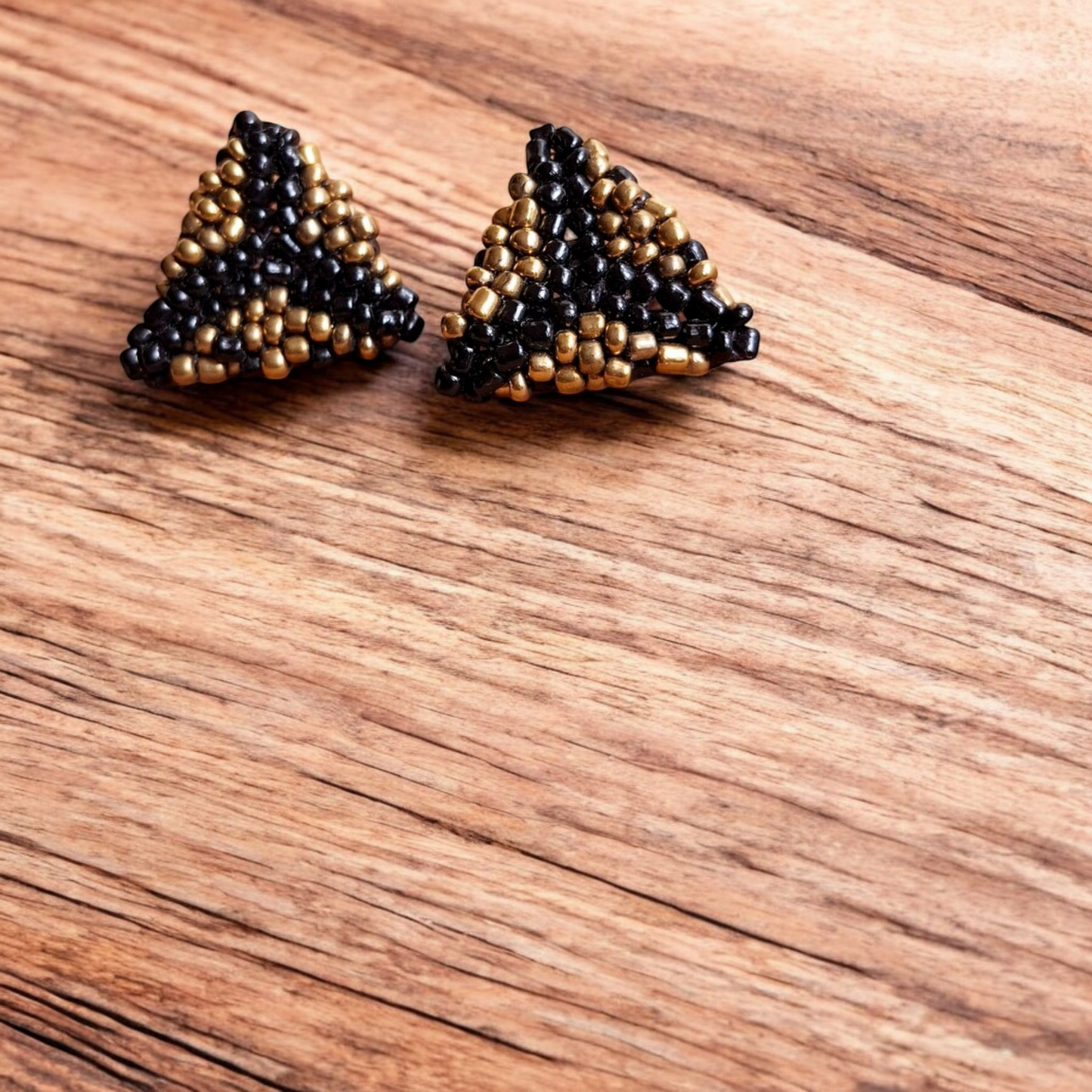 Handmade Pyramid Stud earring in bronze and black with a sleek triangular design on a wooden backdrop.