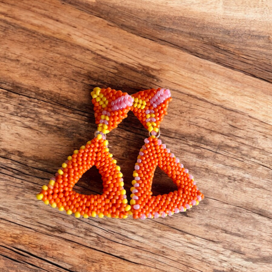 Handmade Paired Peaks earring featuring two stacked triangles in tangerine orange with hints of yellow and pink on a wooden background.