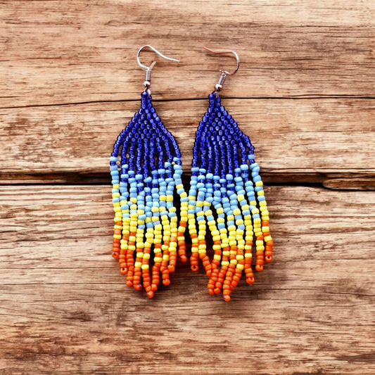 Handmade cascade earring inspired by the rainbow with a curated selection of hues and artistic design on a wooden plate.