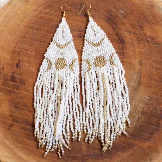 Handmade cascade earrings inspired by the moon, featuring a refined white and gold graceful colors design on a wooden plate.